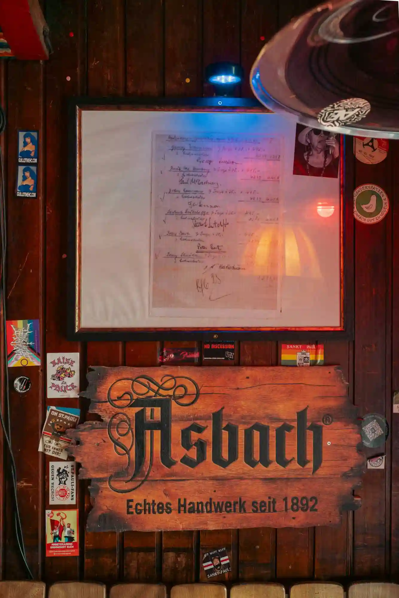 An der Wand von Rosis Bar hängt eine Kopie einer alten Abrechnung auf der alle Beatles unterschrieben hatten. Darunter ist ein Holzschild auf em Asbach steht.